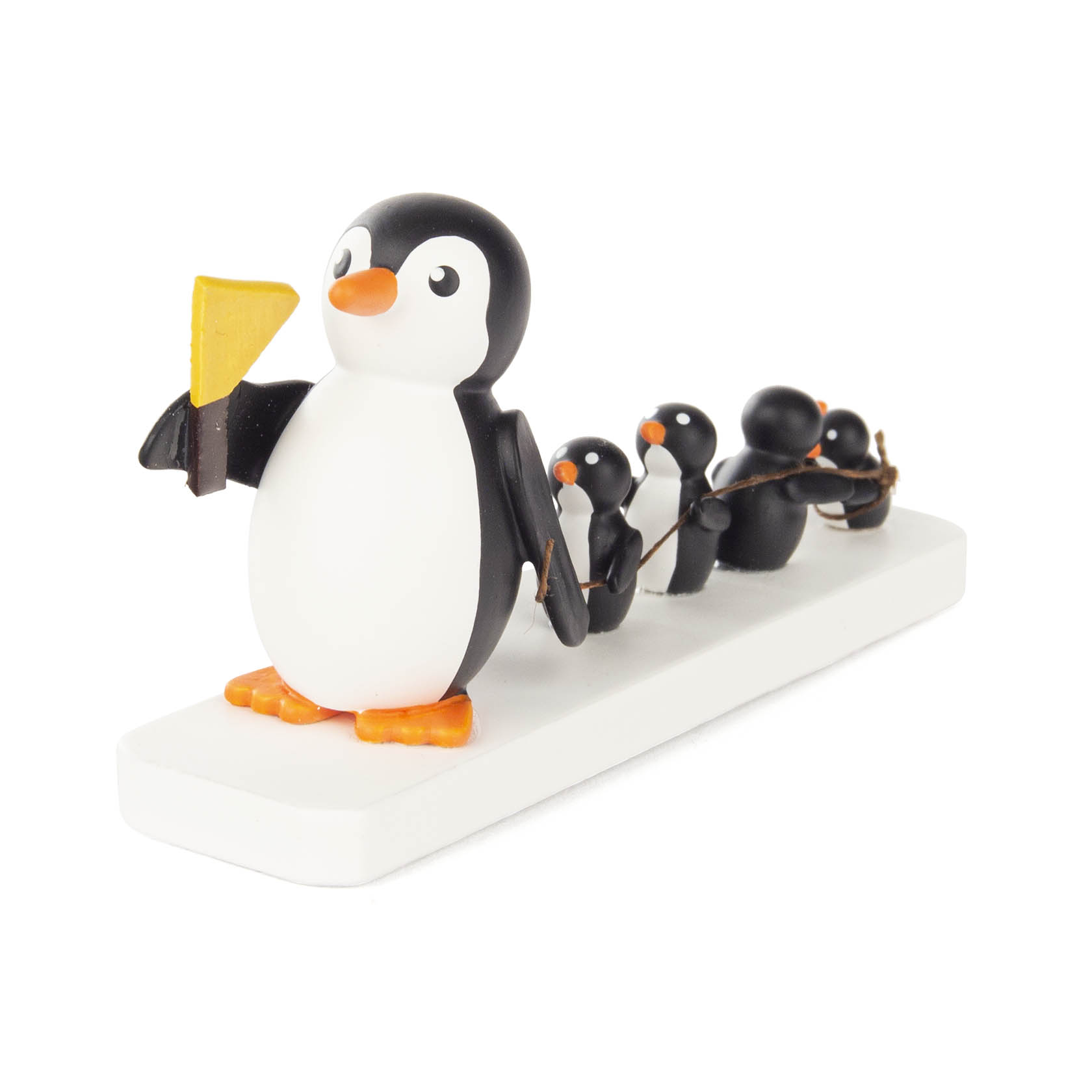 Vier Spielzeug-Pinguine stehen in einer Reihe auf einer weißen Plattform, verbunden durch ein Seil. Der vordere Pinguin hält eine gelbe Fahne. im Dregeno Online Shop günstig kaufen