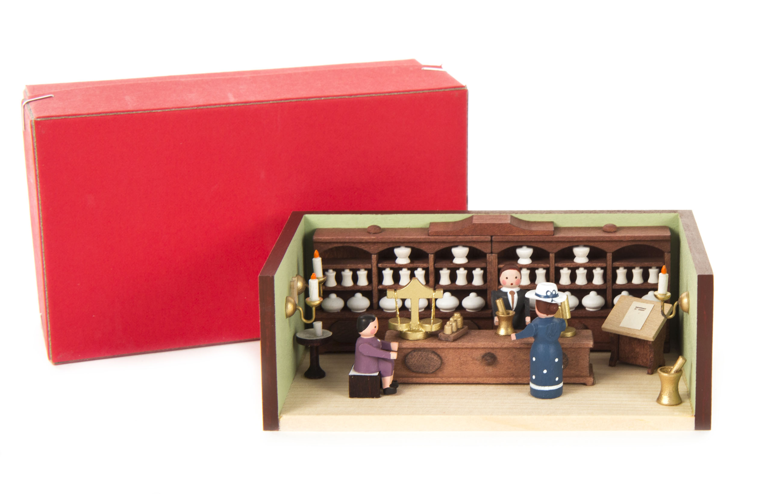 Miniaturmodell einer Apotheke mit einem Apotheker hinter einem Tresen und zwei Kunden, die aus Holzfiguren bestehen. Genauigkeit bei Details und Farben.