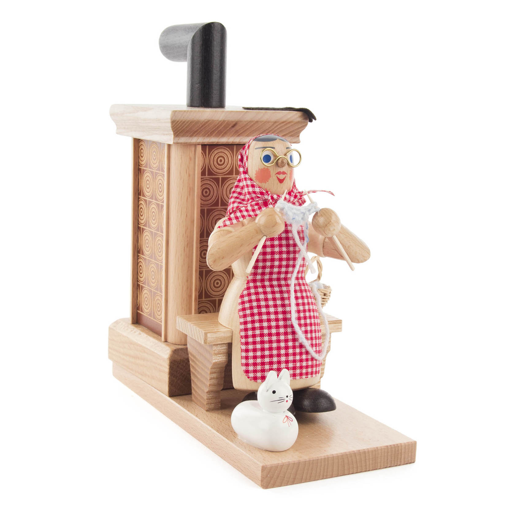 Holzfigur einer sitzenden Oma mit Kopftuch, Strickzeug und Katze, vor einem kleinen dekorativen Räucherofen.