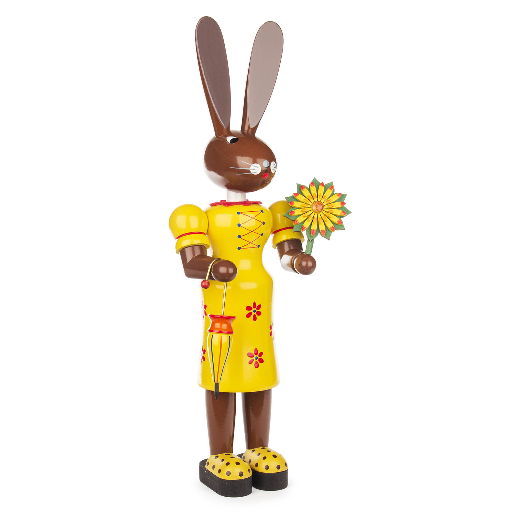 Holzfigur einer Hasenfrau mit braunem Kopf und großen Ohren, in einem gelben Kleid mit rotem Muster. In der Hand hält sie eine bunte Blume. im Dregeno Online Shop günstig kaufen