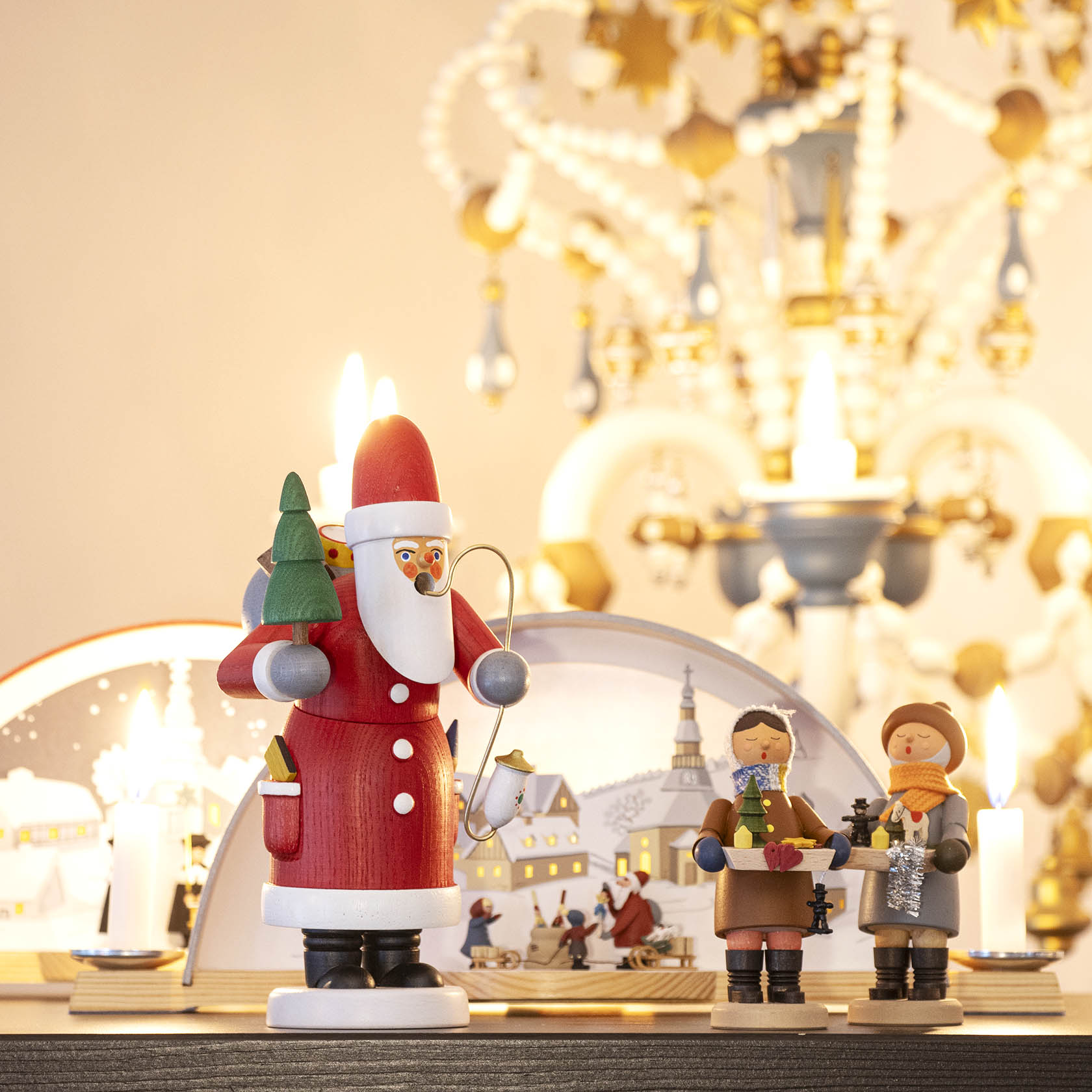 Zwei detailreiche Striezelkinder-Figuren aus Holz stehen auf einem Regal, begleitet von einer größeren Weihnachtsfigur als Weihnachtsmann.
