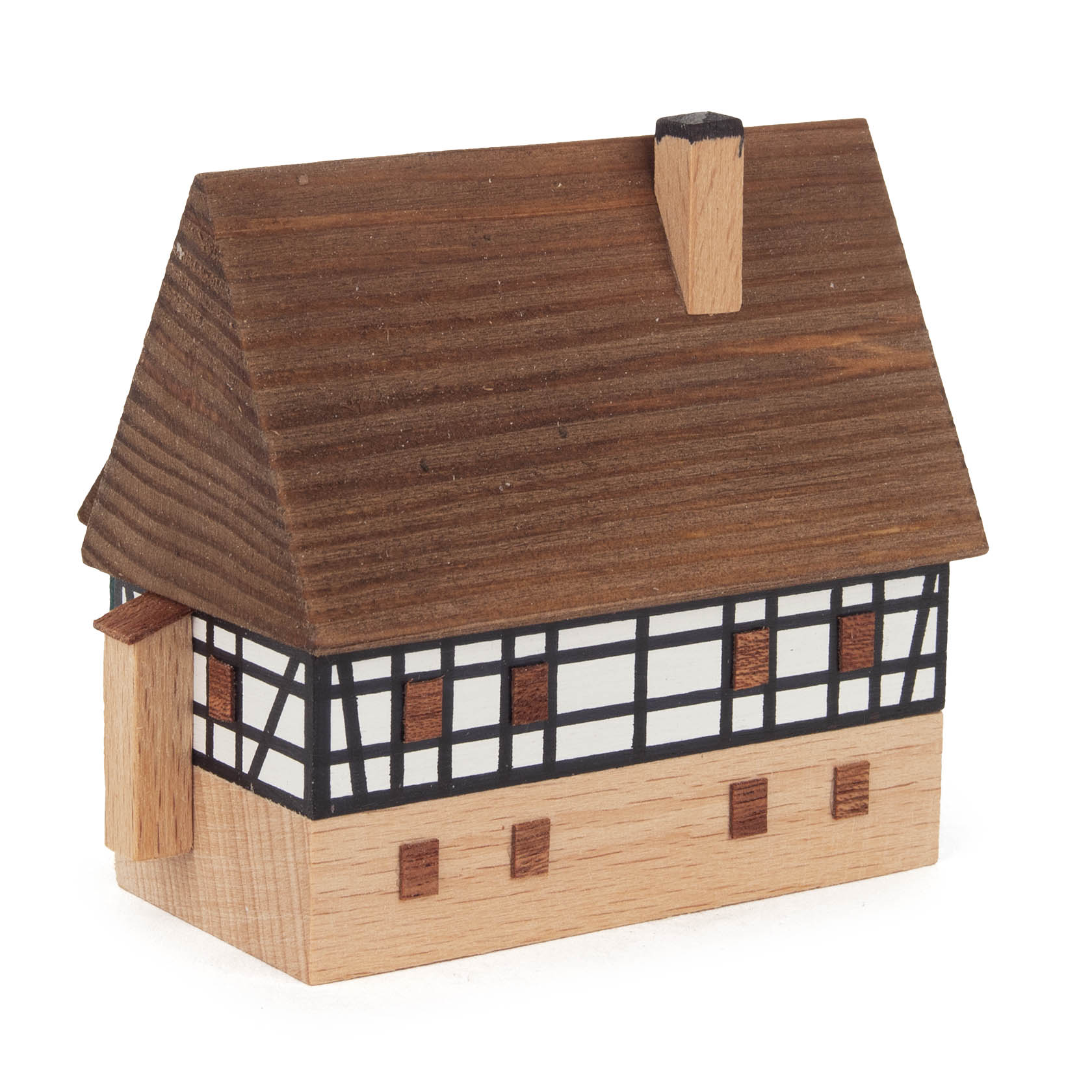 Ein kleines Miniaturmodell eines Fachwerkhauses mit Holzverkleidung, braunem Gefach und einem Schornstein.