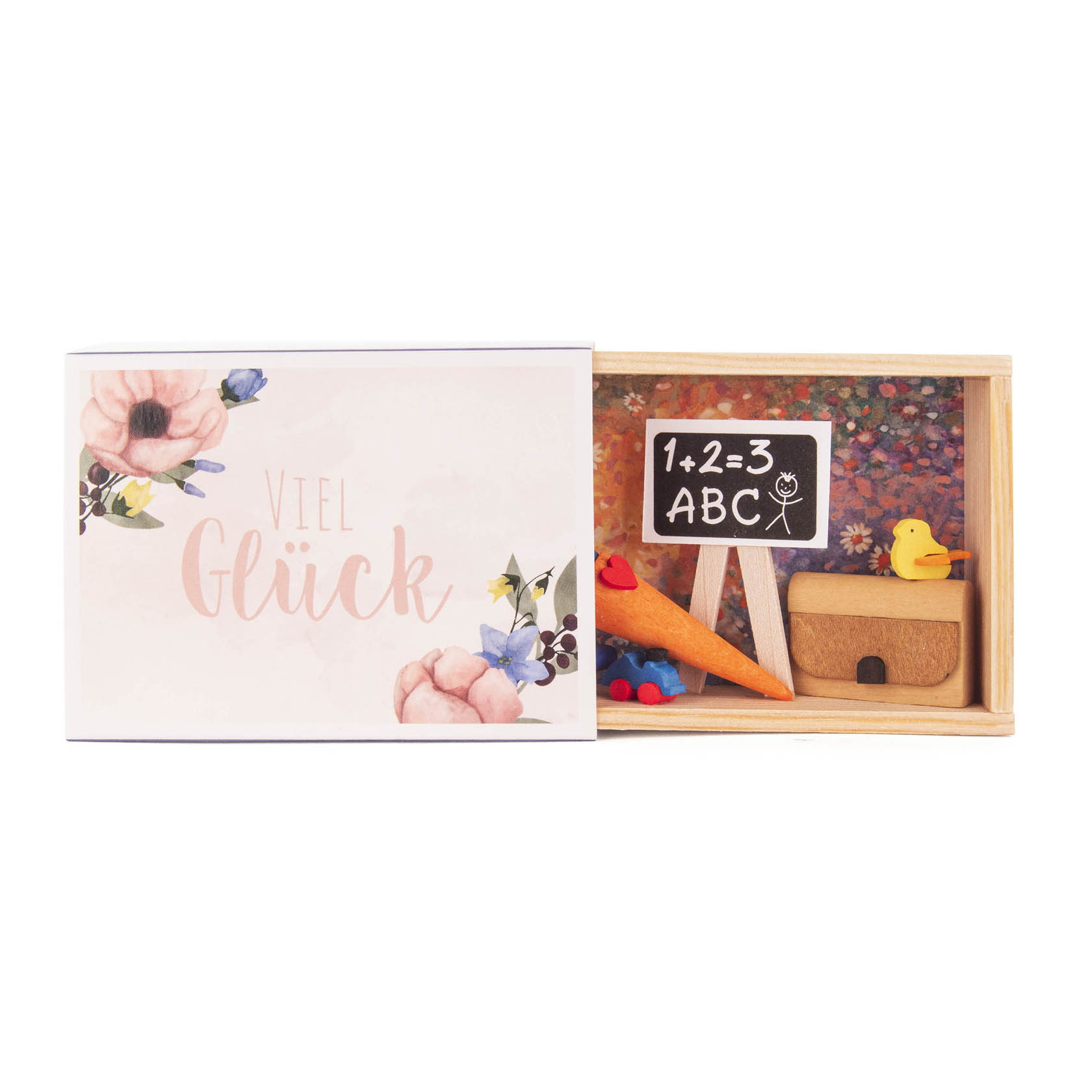 Kleine Holzbox mit der Aufschrift 'Viel Glück' und Blumenmotiv. Geöffnet zeigt sie Miniatur-Schulmaterialien wie Tafel, Kreide, Stifte und eine Ente. im Dregeno Online Shop günstig kaufen