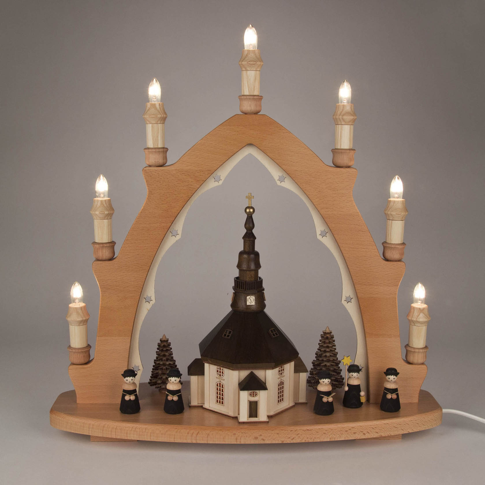 A traditional wooden arch candle holder featuring the Seiffen Church with Kurrende singers, electrically lit, with an illuminated interior.