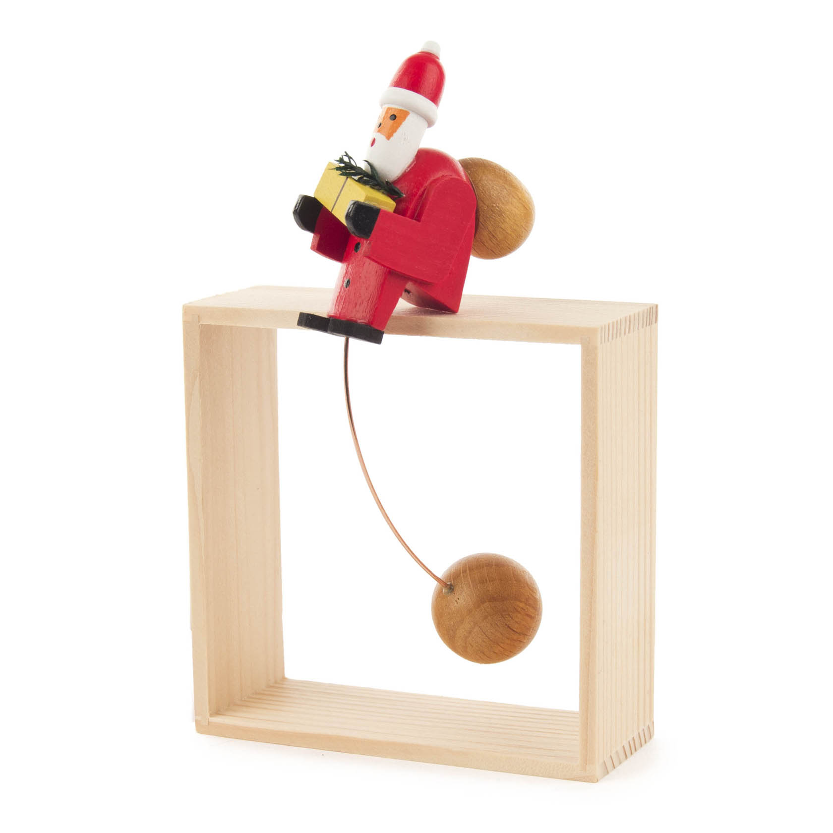 Kleine Schaukelfigur eines Weihnachtsmanns, der ein Geschenk hält und auf einem Holzrahmen balanciert. Der Weihnachtsmann hat eine rote Mütze und einen roten Anzug.