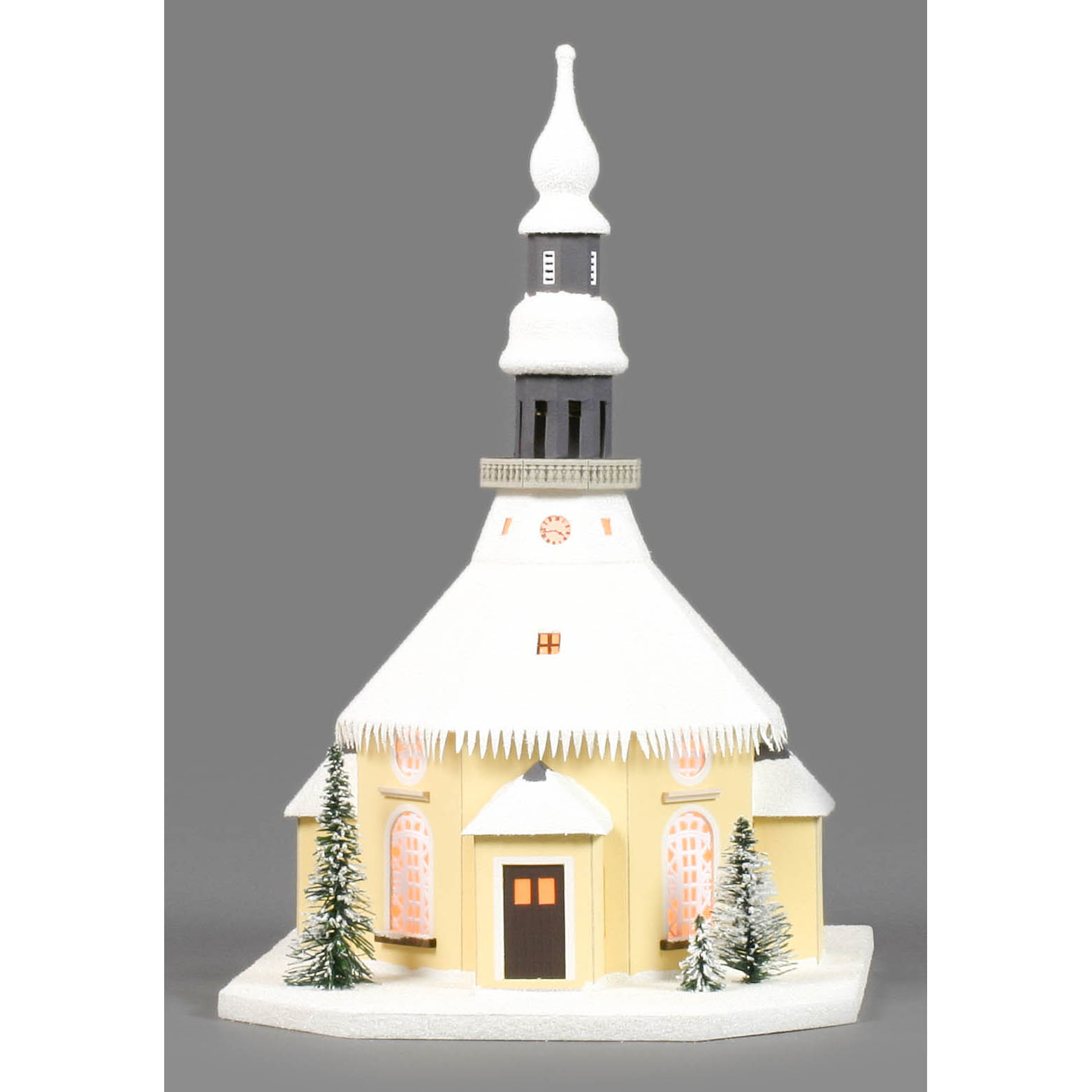 Ein Miniaturmodell der Seiffener Kirche mit schneebedecktem Dach, elektrische Beleuchtung, und dekorativen Tannenbäumen.