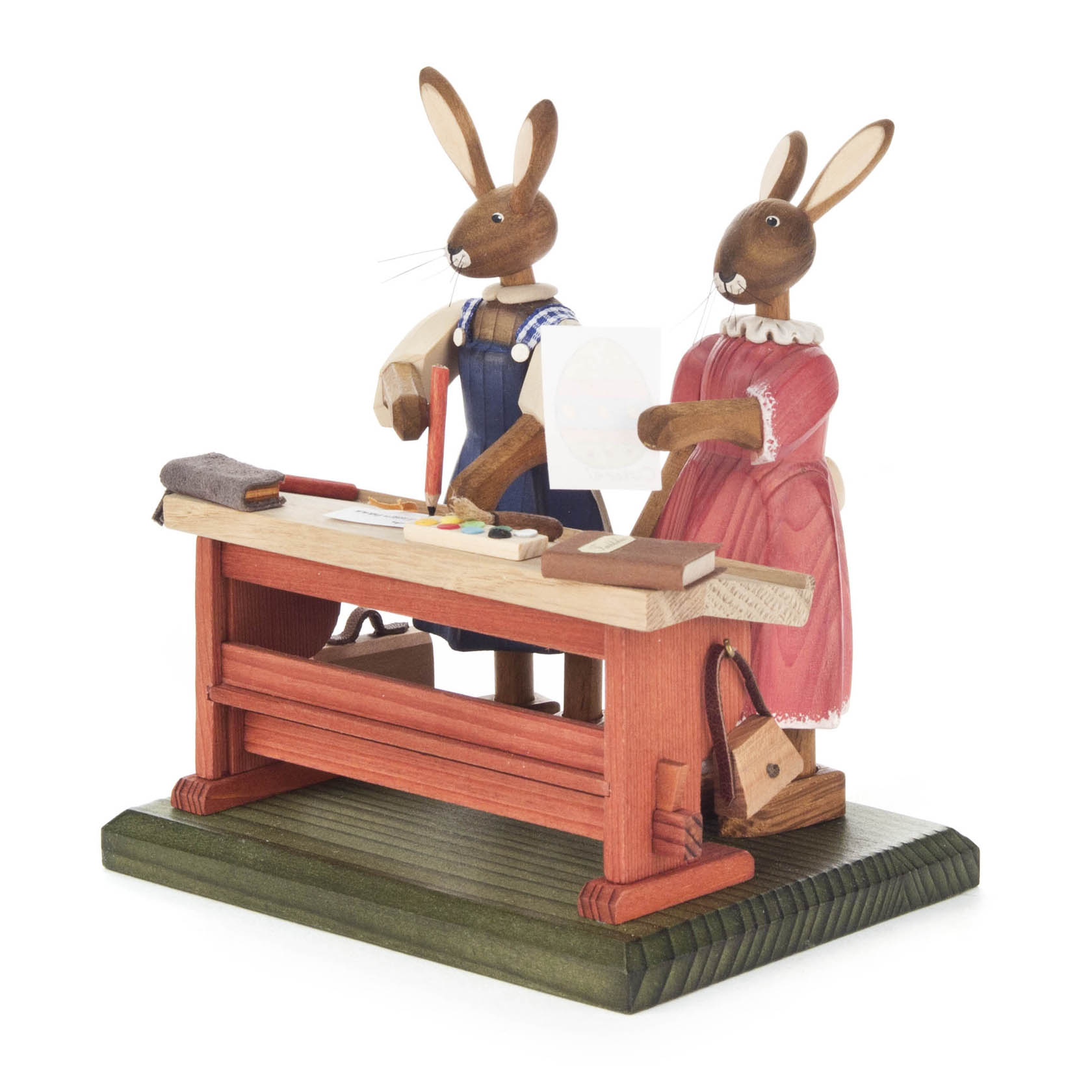 Zwei Hasen in Kleidung stehen an einer Holzwerkbank. Der Hase links trägt Blaumann, der Hase rechts ein rosa Kleid. Auf dem Tisch liegen Holzstücke. im Dregeno Online Shop günstig kaufen