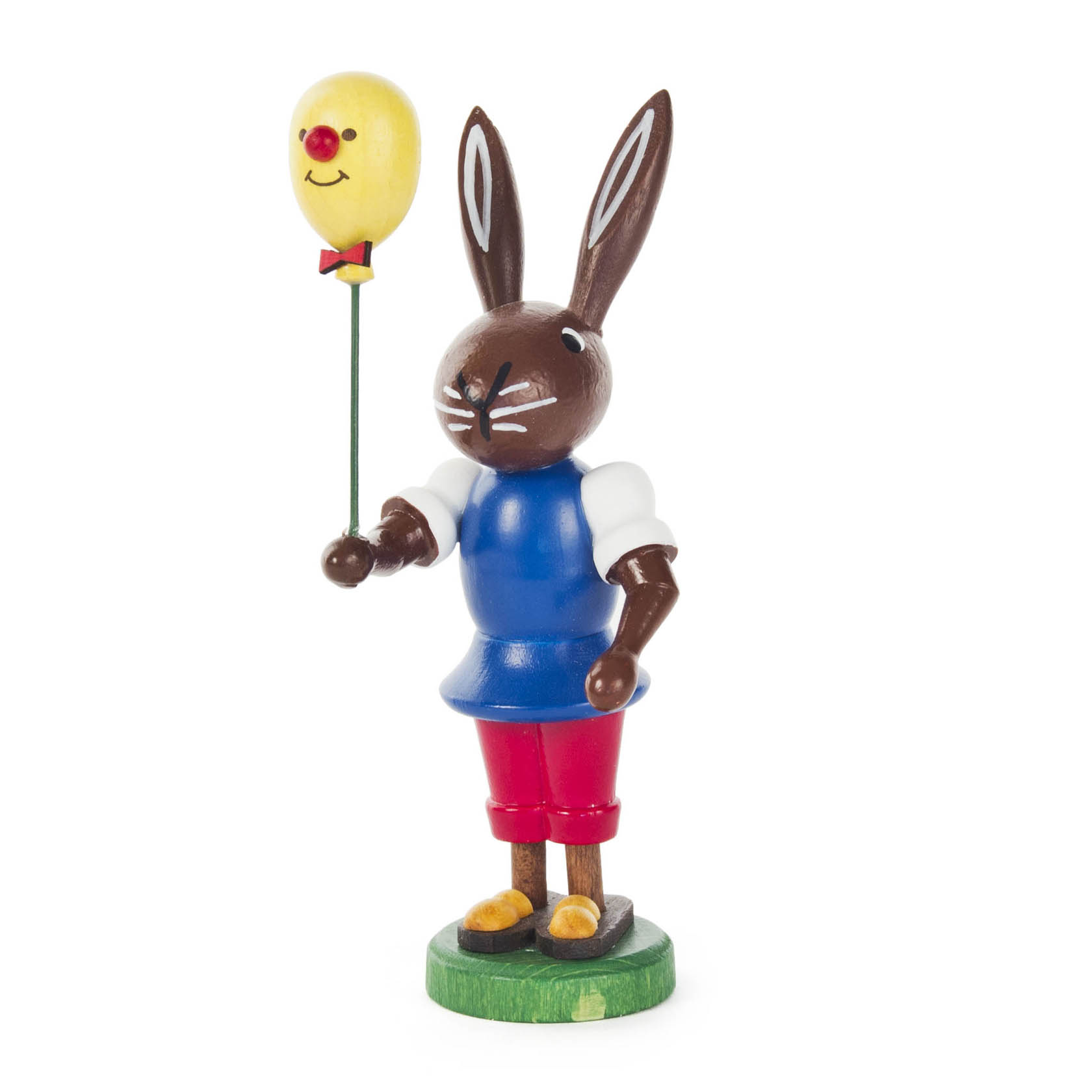 Holzfigur eines Hasen in blauer Kleidung, der einen gelben Luftballon mit Gesicht in der linken Hand hält. im Dregeno Online Shop günstig kaufen