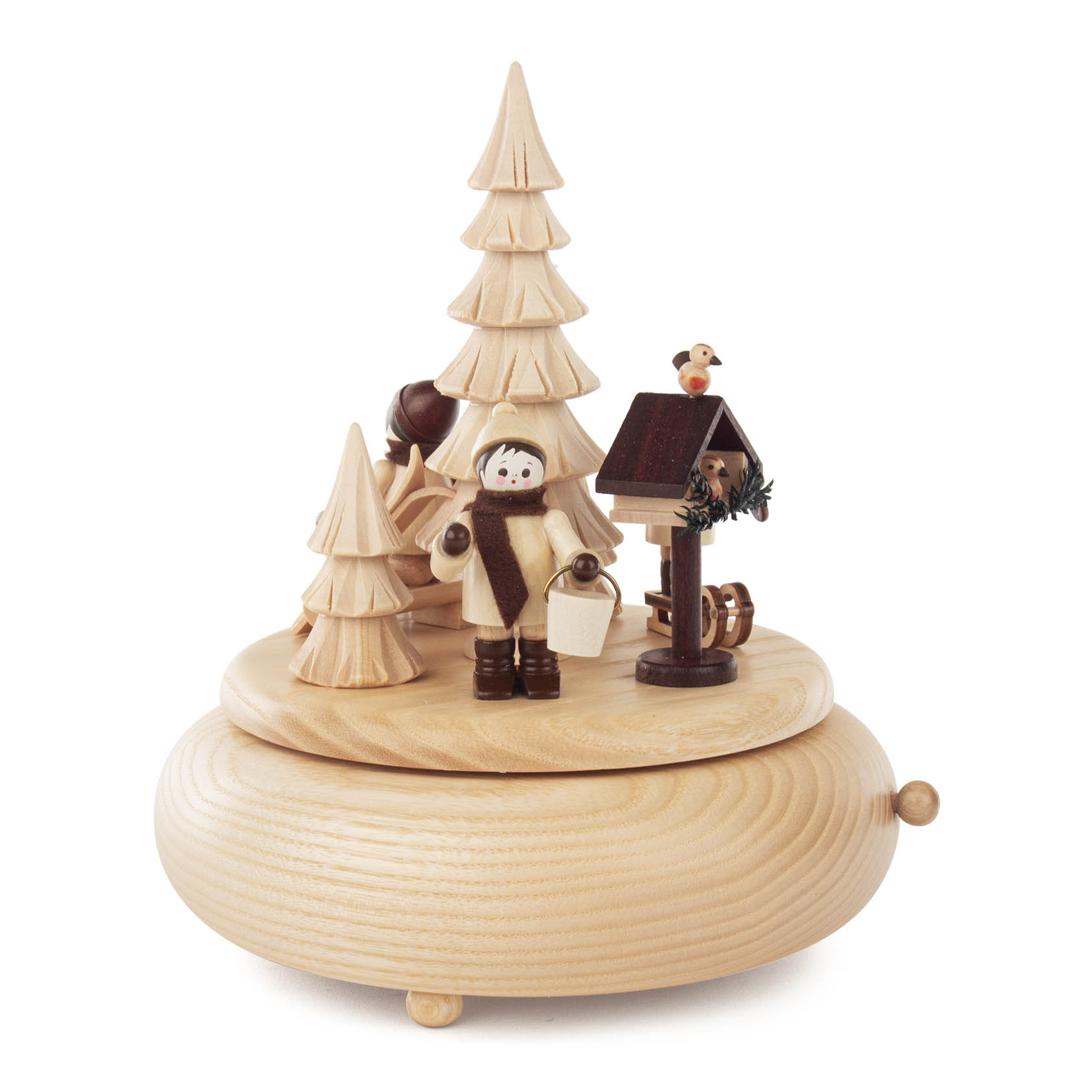 Holzspieldose mit winterlicher Szene: Ein Kind steht mit einem Futtereimer vor einem Vogelhaus, ein Vogel sitzt darauf, umgeben von hohen Tannenbäumen. im Dregeno Online Shop günstig kaufen