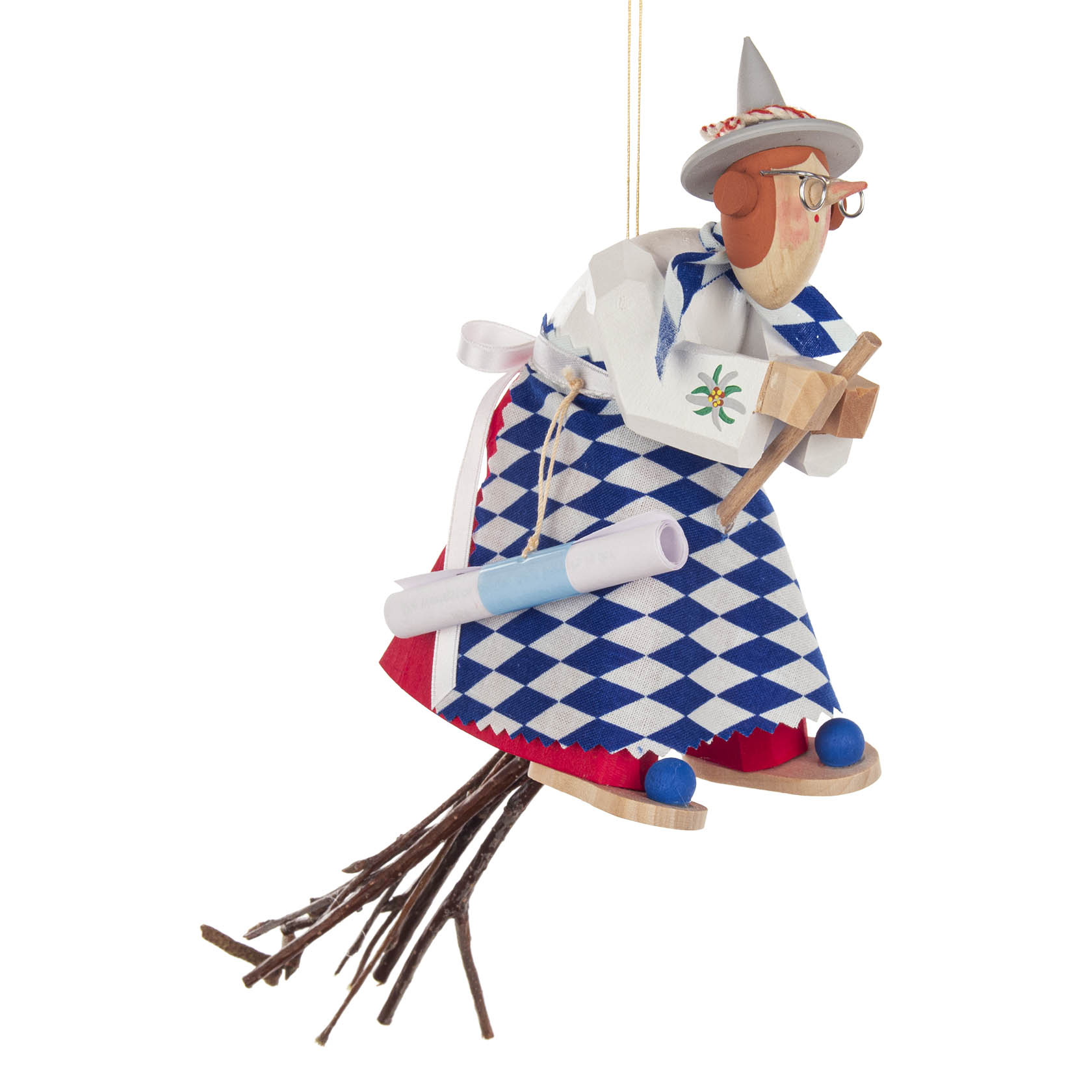 Dekorative Figur einer bayerischen Hexe mit Brille und grauem Hut. Sie trägt ein blau-weiß kariertes Kleid und fliegt auf einem Besen aus Zweigen. im Dregeno Online Shop günstig kaufen