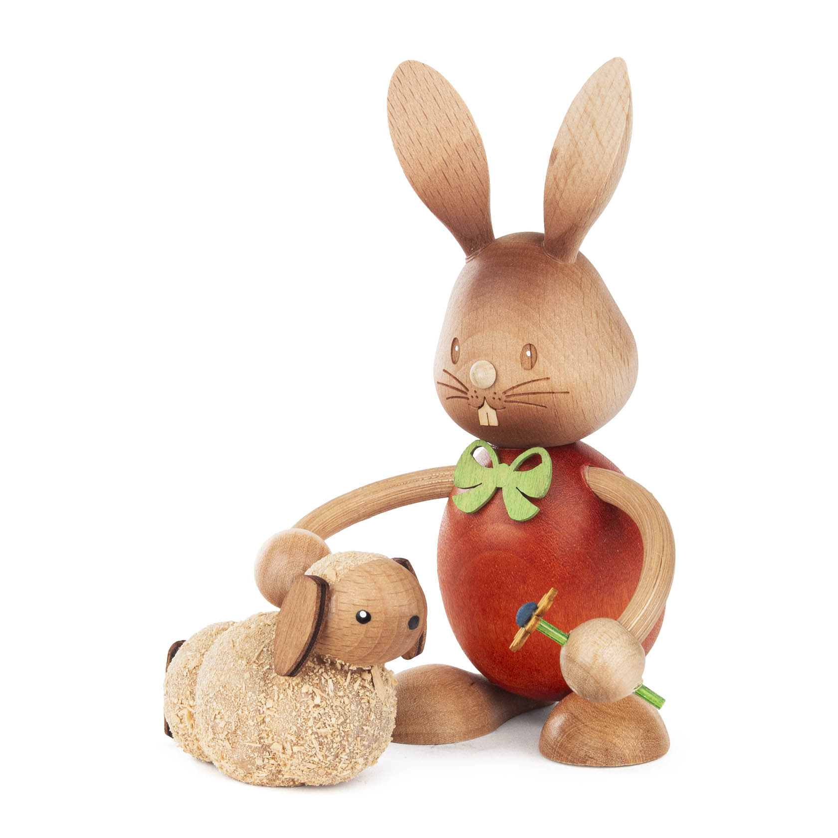 Holzfigur eines Hasen namens Stupsi mit einer Karotte, hockend neben einem kleinen, liegenden Lamm. Beide sind liebevoll verziert und aus Holz gefertigt. im Dregeno Online Shop günstig kaufen