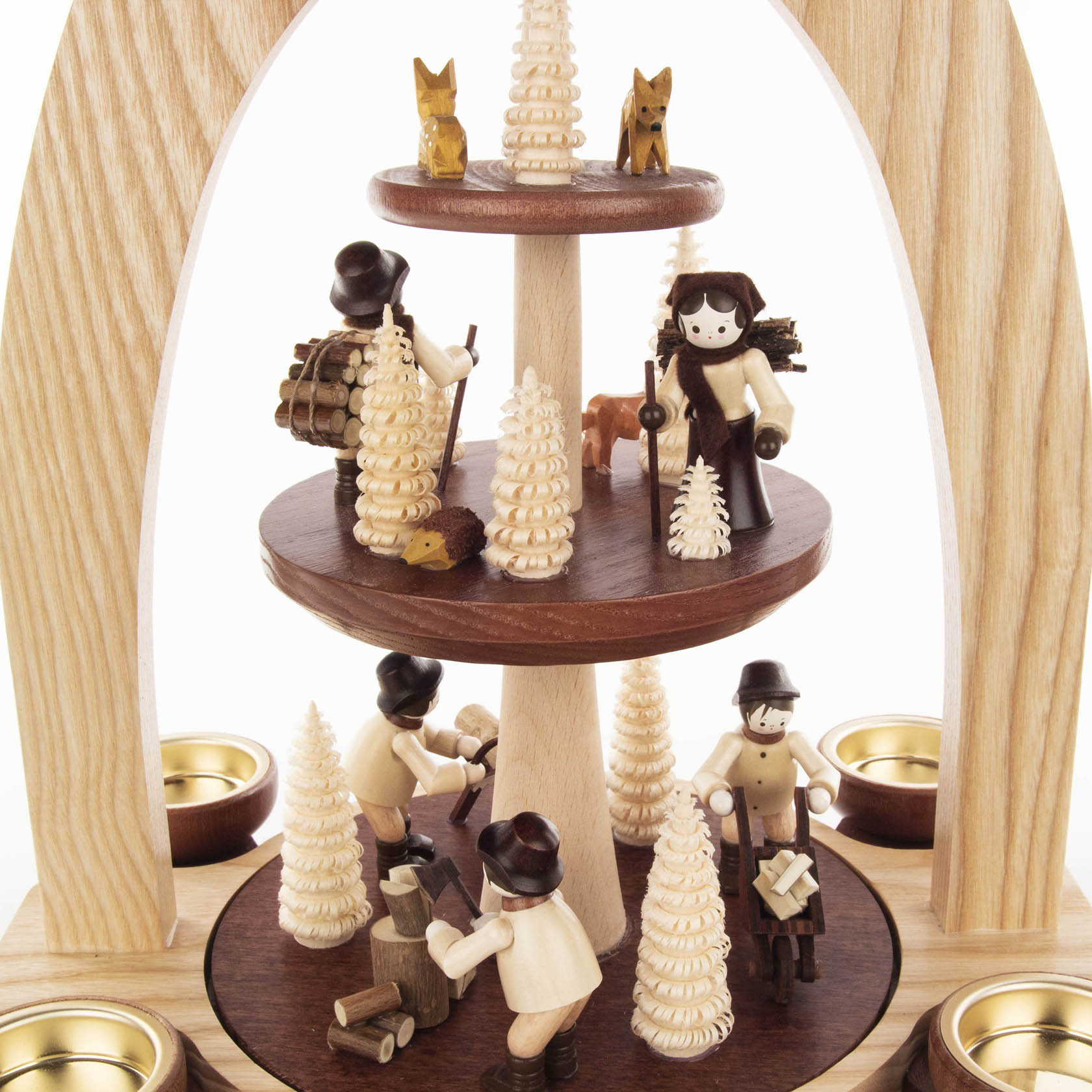 Dreistöckige Pyramide aus Holz mit Figuren von Waldleuten und Tieren, verziert mit filigranen Bäumen. Unten Holzfäller, in der Mitte Wanderer, oben Füchse.