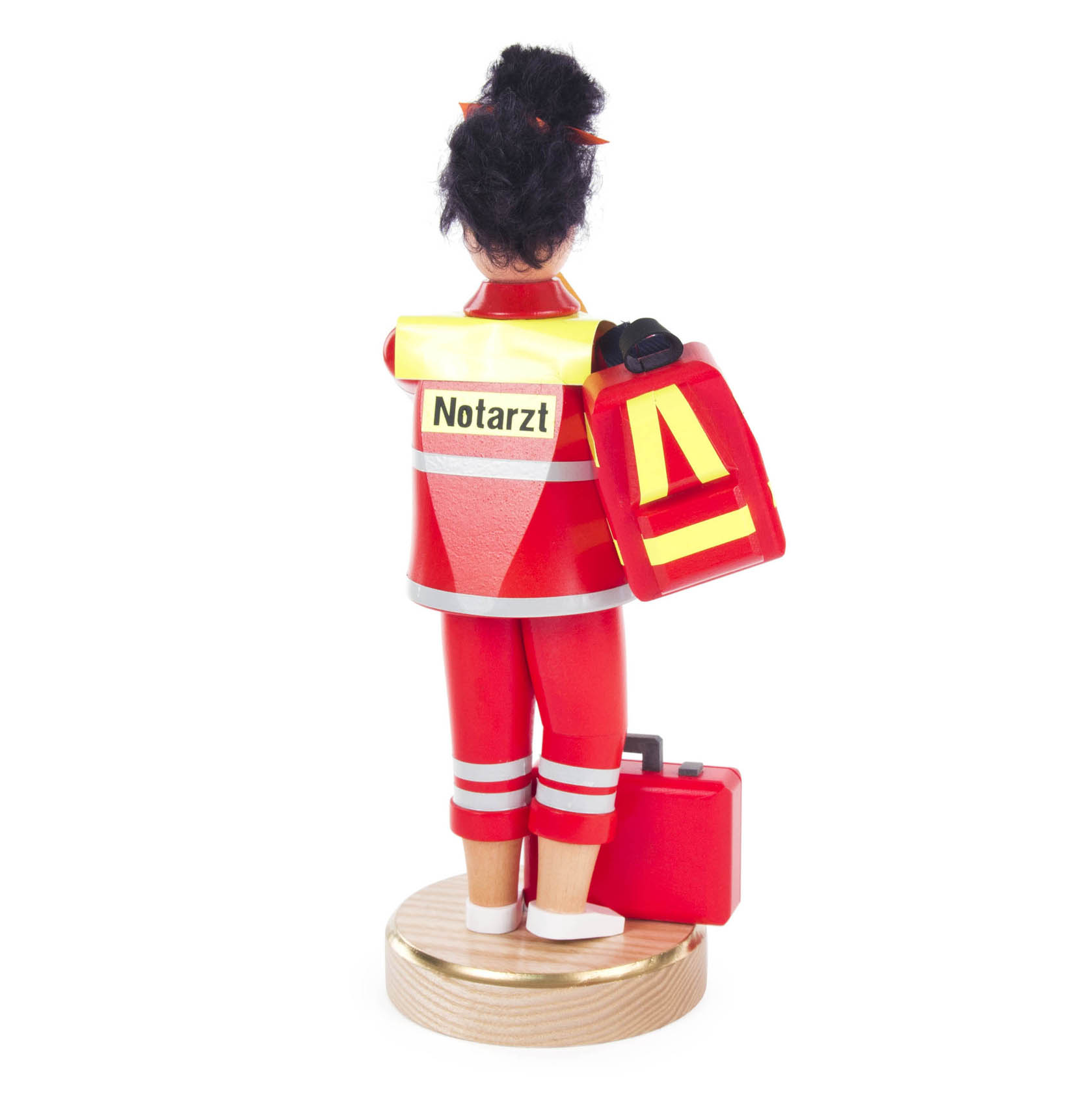 A wooden figurine of a female emergency doctor wearing a red uniform with reflective stripes, holding a red medical bag.