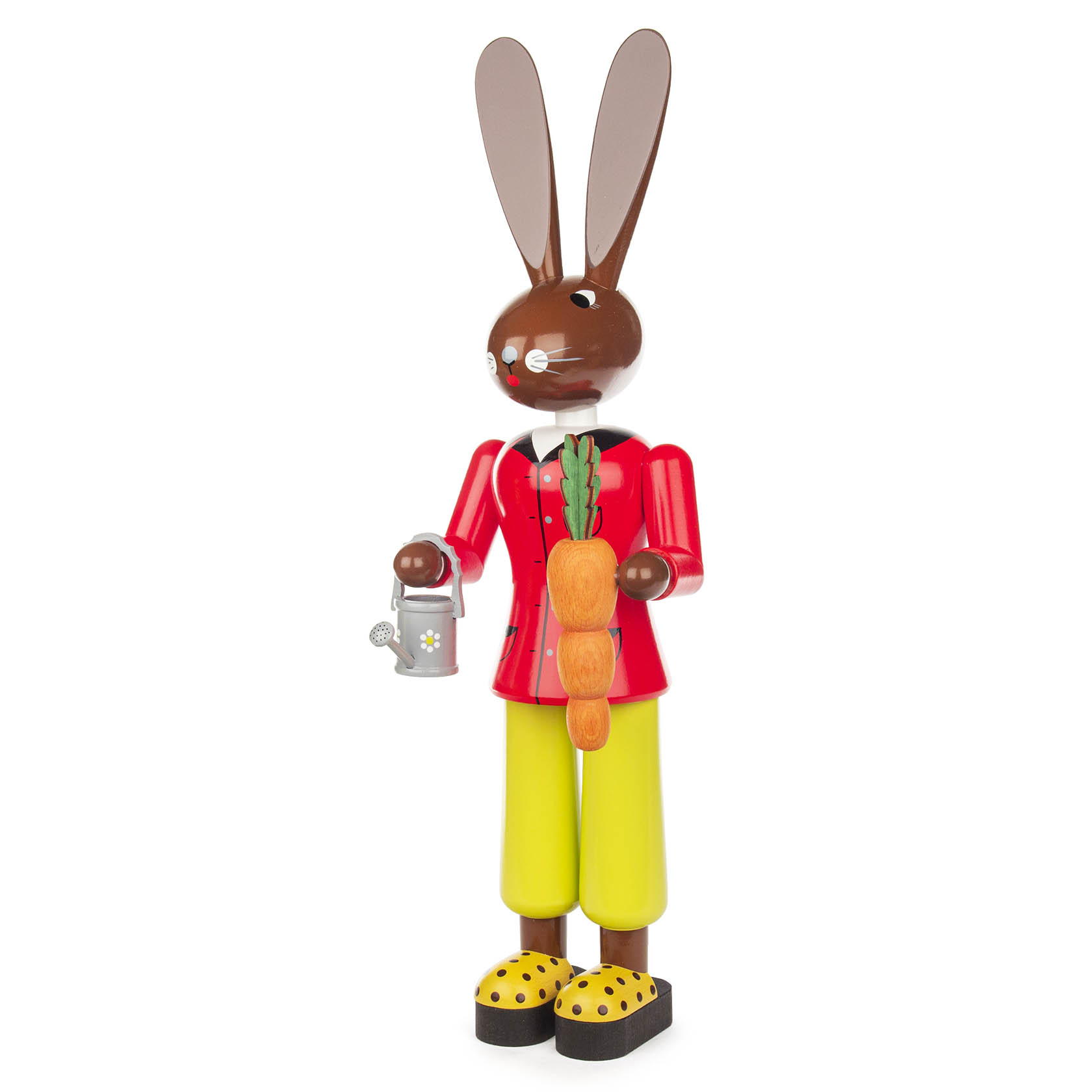 Holzfigur eines Hasen in roter Jacke und gelber Hose, der eine Gießkanne hält und eine große Karotte um den Hals trägt.