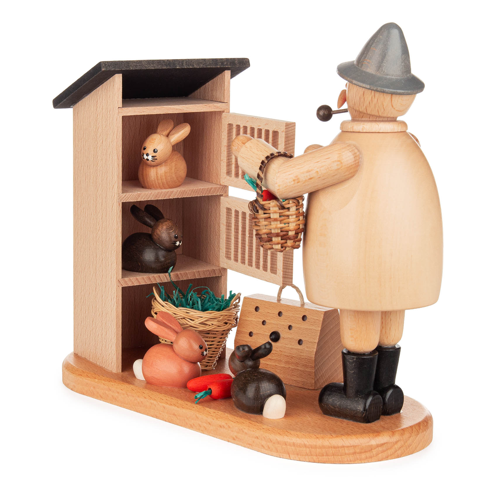 Holzfigur eines Kaninchenzüchters mit Pfeife, die vor einem Schrank mit vier Kaninchen steht. Ein Kaninchen sitzt im Korb, andere auf dem Boden mit Karotten.